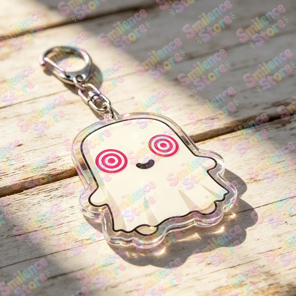 A clear, cute ghost-shaped keychain charm with pink and white details resting on a wooden surface.