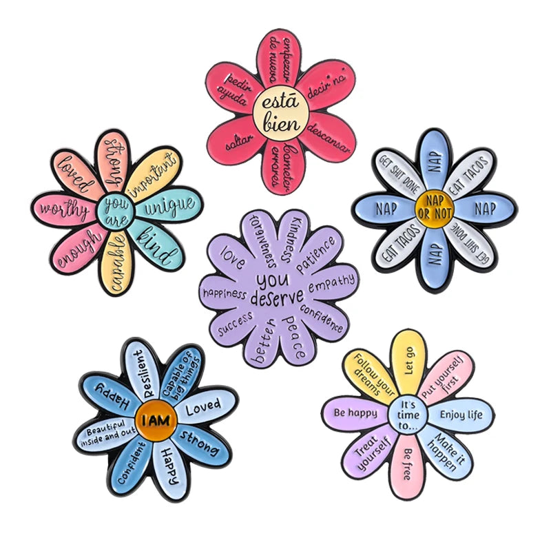 A set of enamel flower brooches featuring positive affirmations like Be kind and You deserve better.