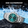 A stainless steel watch with a teal face and silver band is shown resting on a dark rock.