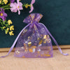Purple sheer satin drawstring jewelry pouch with gold floral embroidery resting on a light fabric.