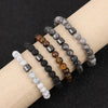 A collection of Tiger Eye lava map bracelets in various shades and textures displayed on a beige fabric background.