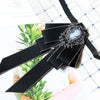 A black rhinestone bow tie neck tie with a silver stone embellishment shown against a light background.