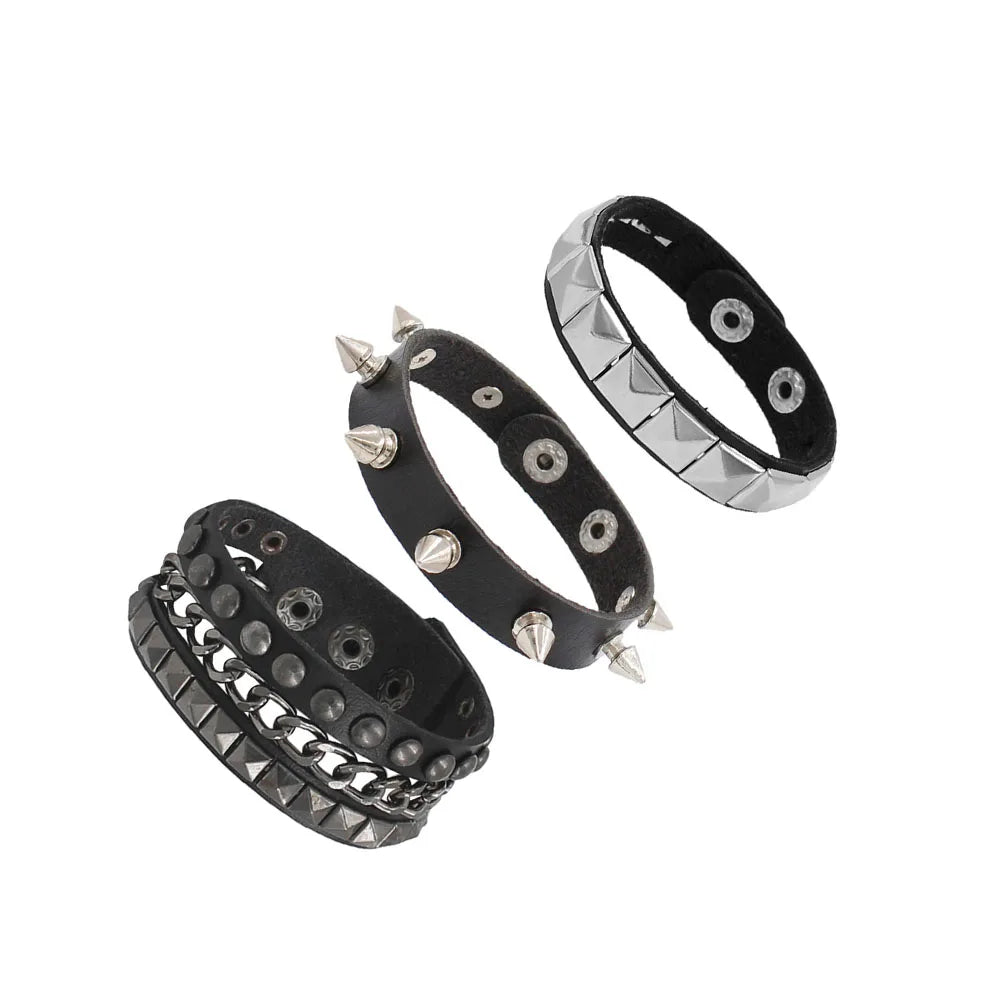 Un set de trois bracelets de poignet en cuir cloutés style punk rock, métal noir et argent.