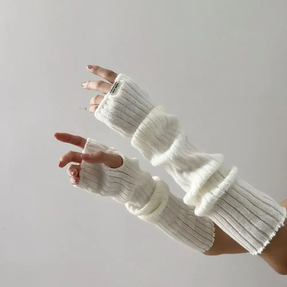 A hand wearing white fingerless arm warmers, showing the knitted texture and fit.