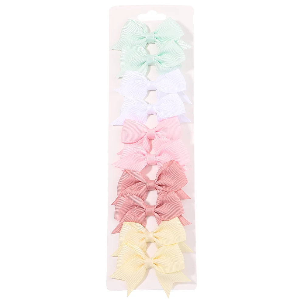 Un set de clips para el pelo en forma de lazo de colores sólidos infantiles en tonos pastel, incluyendo verde menta, verde cl