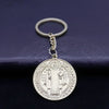 Silver round medallion keychain featuring a religious figure and text on a dark blue background.