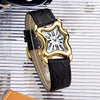 A gold-toned fashion quartz wristwatch with a Roman dial and black leather strap resting on a white striped surface.
