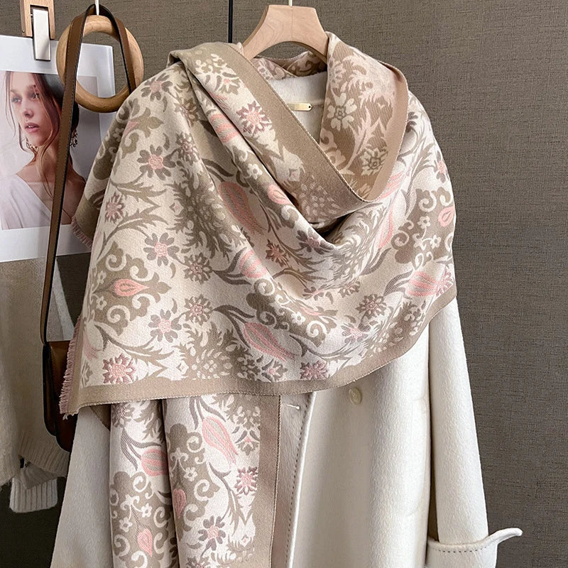 A beige and pink floral patterned cashmere scarf draped around a light-colored coat.