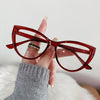 Eine Hand hält eine rote Vintage Cat-Eye-Lesebrille mit Goldakzenten vor weißem Hintergrund.
