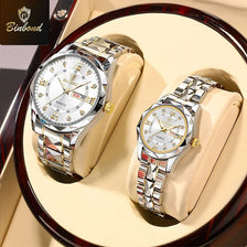 A pair of stainless steel couple watches displayed on light-colored leather pads.