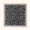 Schwarz-weißes Blumenmuster auf einem weißen Stoffquadrat.