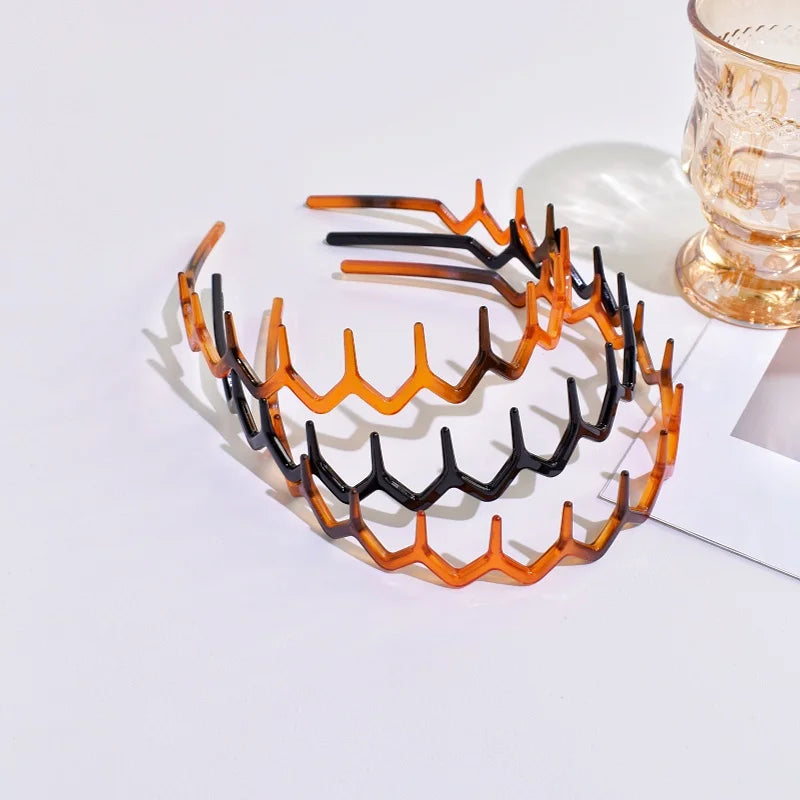 A set of textured hair bands in shades of orange and black displayed on a white surface.