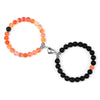 A pair of natural stone heart couple bracelets, one orange and one black, displayed against a white background.