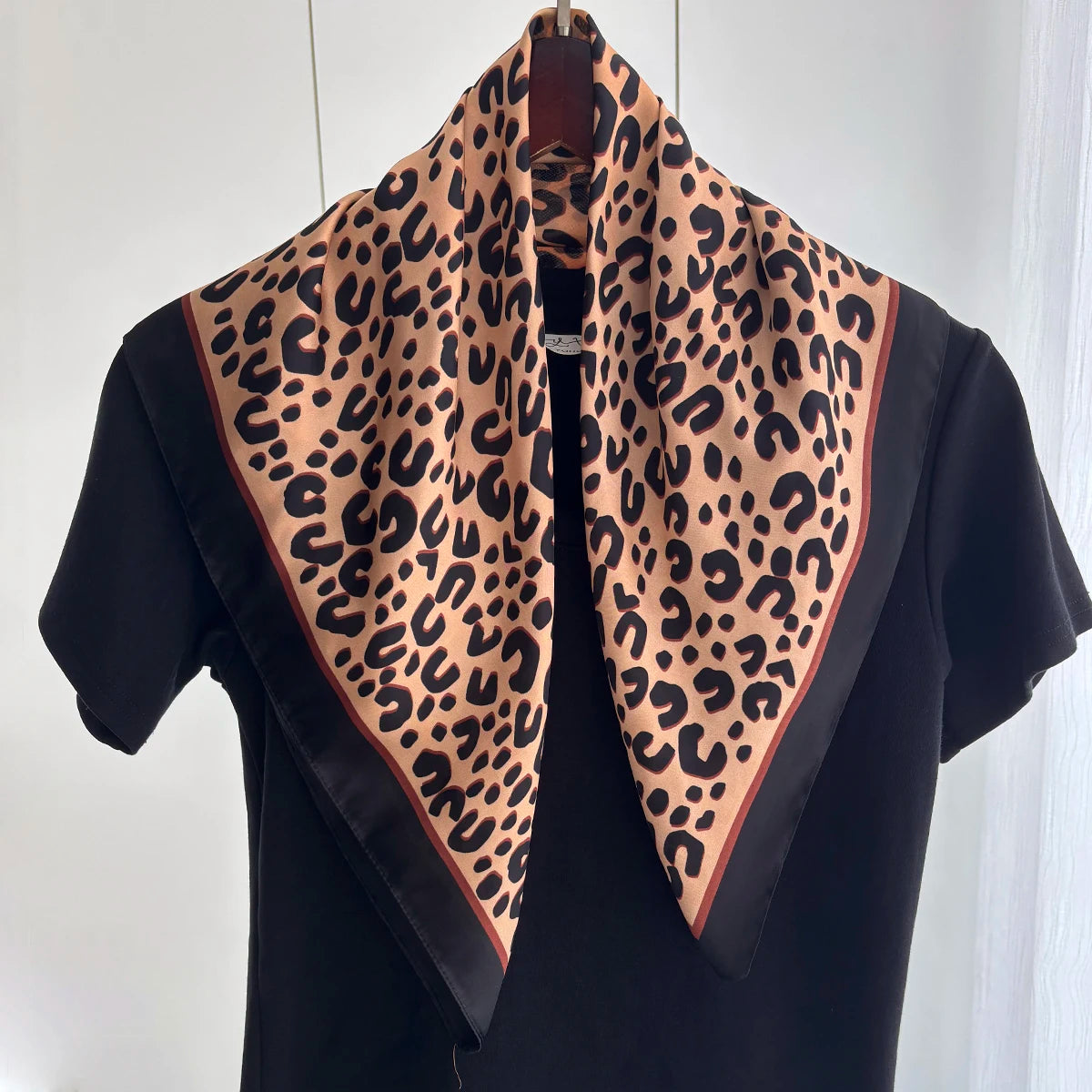 A black blouse with a leopard print silk scarf draped around the neck and shoulders.