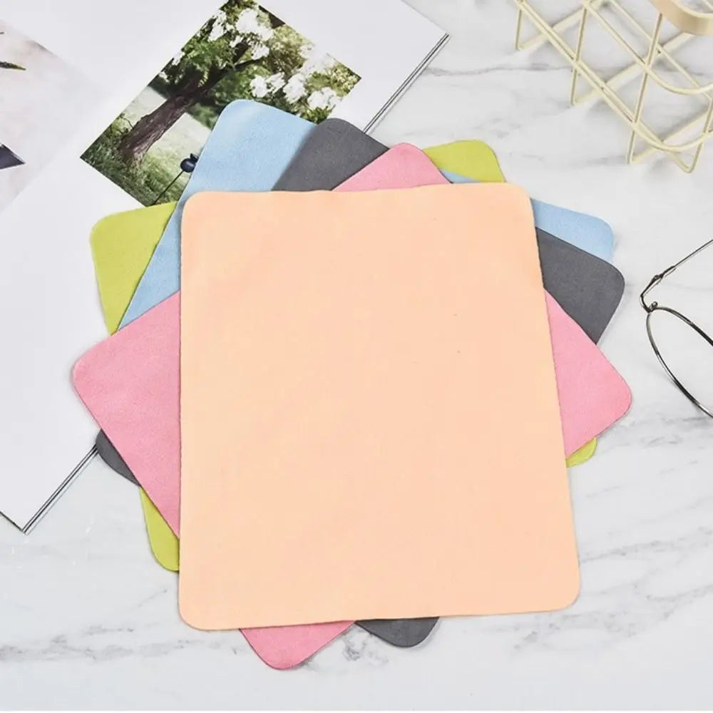 Un juego de paños de limpieza de gamuza multicolor para gafas, con varios tonos pastel apilados sobre una superficie blanca.