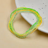 A bracelet of luminous glow-in-the-dark green and yellow beads displayed on a white plate.
