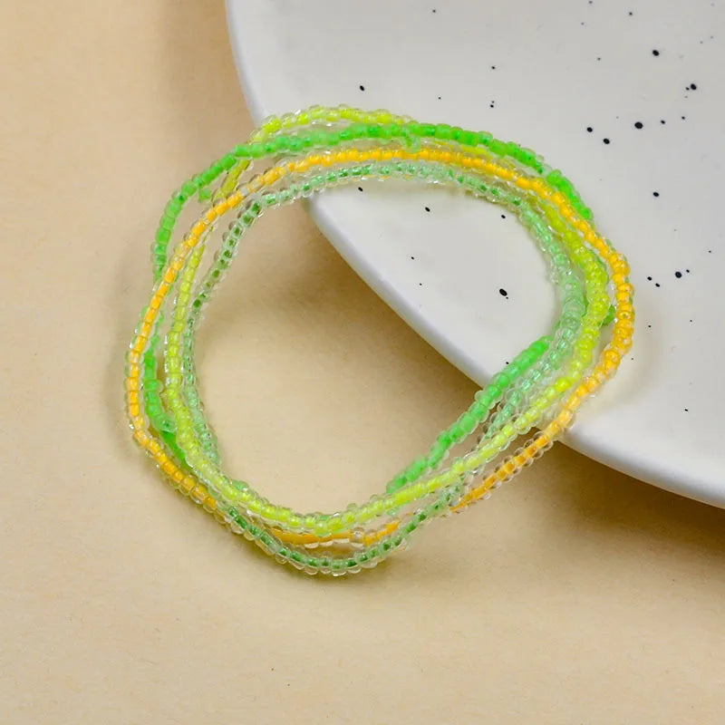 A bracelet of luminous glow-in-the-dark green and yellow beads displayed on a white plate.