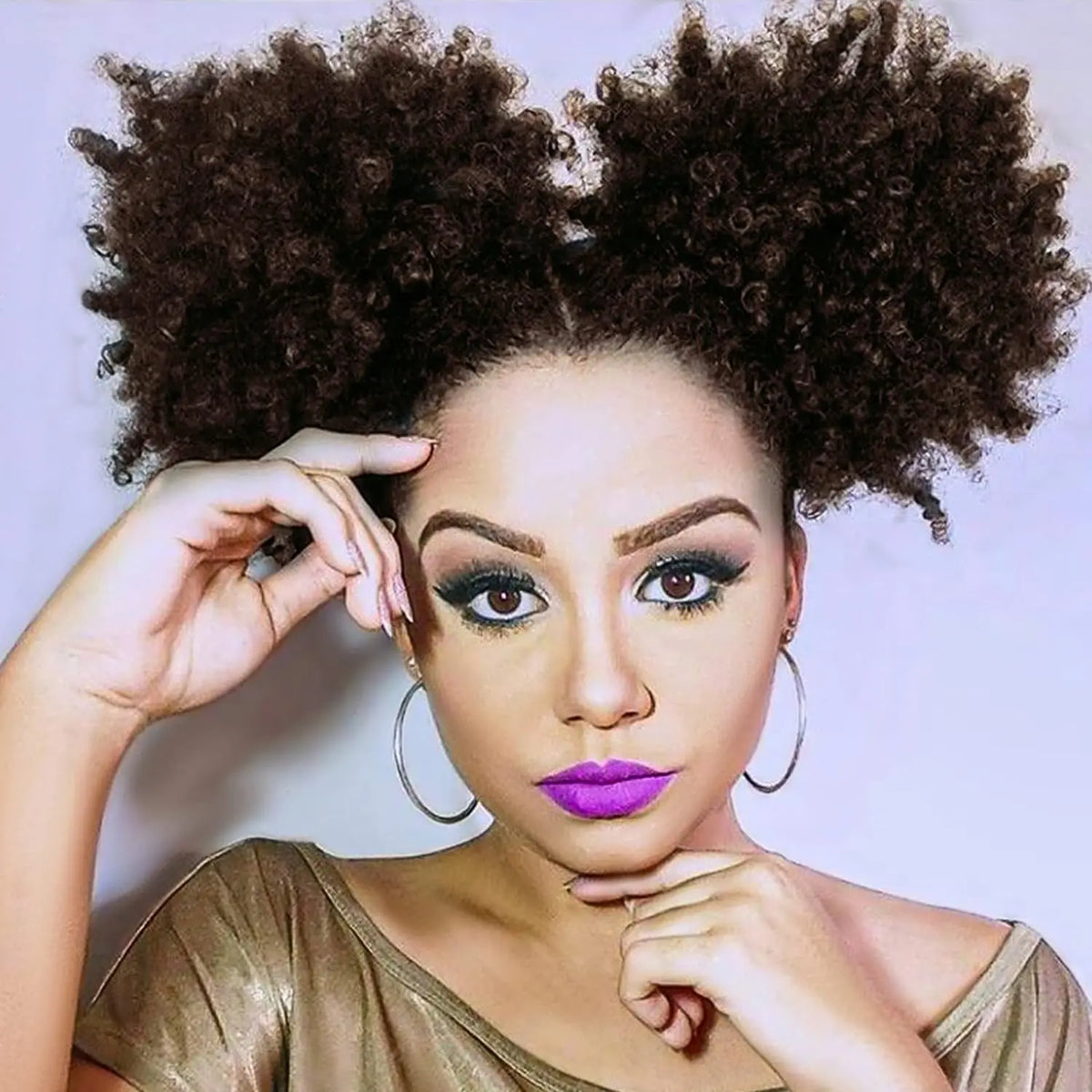 A woman with dark curly hair styled in an afro puff drawstring ponytail looking directly at the camera.