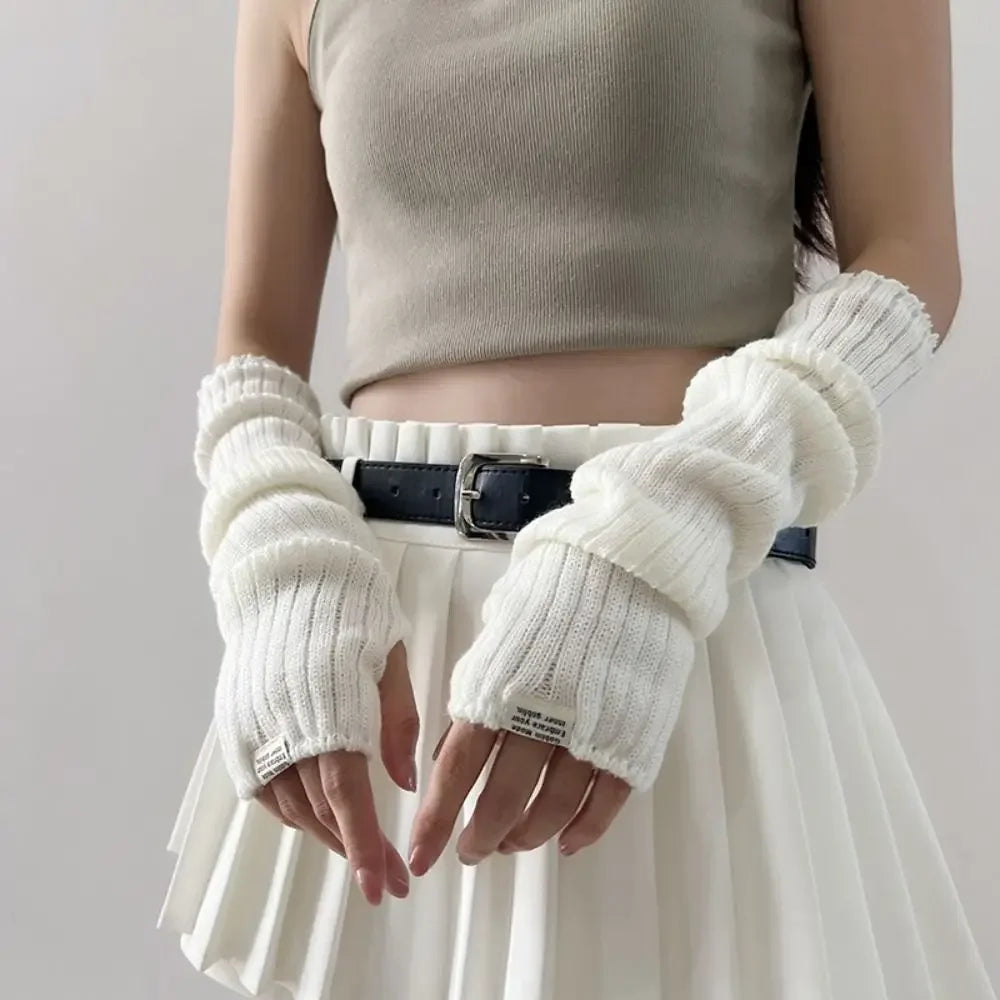 A model wearing fingerless arm warmers and a light top with a pleated skirt.