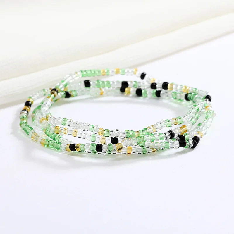Una pulsera hecha de pequeñas cuentas verdes y amarillas con acentos negros.