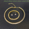 A gold-toned necklace and earring set featuring clear crystals displayed on a dark background.