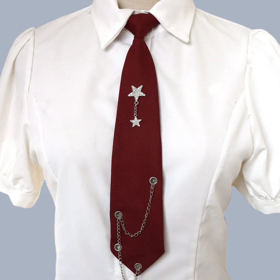 A maroon tie with a silver chain star pendant worn under a white collared shirt.