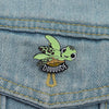 A green sea turtle enamel lapel pin brooch is pinned onto a blue denim fabric.