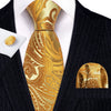 A close-up of a men's silk jacquard tie in gold and brown paisley pattern worn with a dark suit jacket.