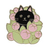 A black cat face surrounded by pink and light green enamel flowers on a brooch.