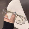 A hand holds a pair of clear wire-frame glasses resting on a white shoe sole.