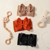 A collection of soft baby headbands featuring chunky hair bows in shades of pink, orange, and black.