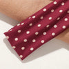 Un bandeau en tissu à pois marron posé sur une surface beige.