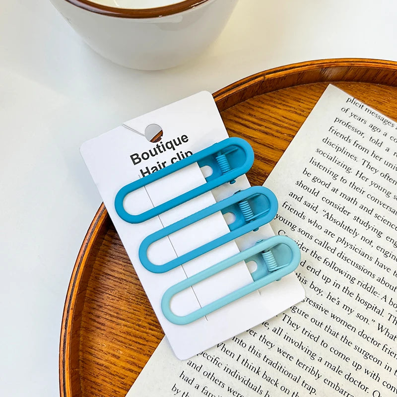 A set of vintage frosted geometry hair clips displayed on a white card next to a piece of paper.