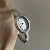 A silver quartz analog watch with an oval face and Roman numerals is shown on a wrist.