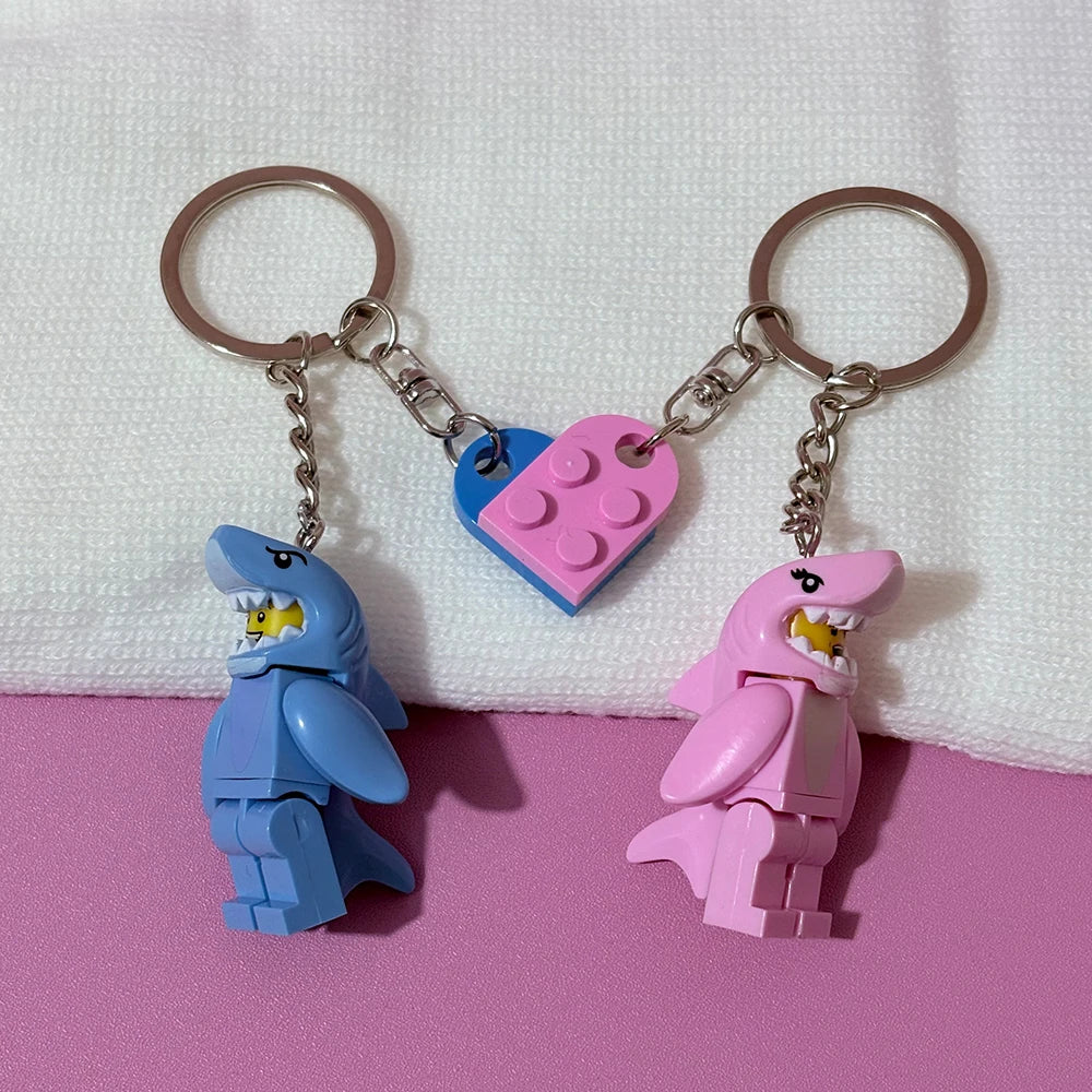 A keychain set featuring two heart-shaped building blocks shaped like sharks in blue and pink.