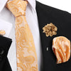Nahaufnahme eines eleganten Herren-Krawattenset mit goldkariertem Seidenschal und passender blumiger Reversspange auf schwarz