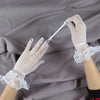 A hand wearing sheer lace fishnet evening gloves is holding a white stick or wire.