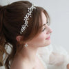 A close-up of a woman with brown hair wearing an elegant pearl bridal headband.