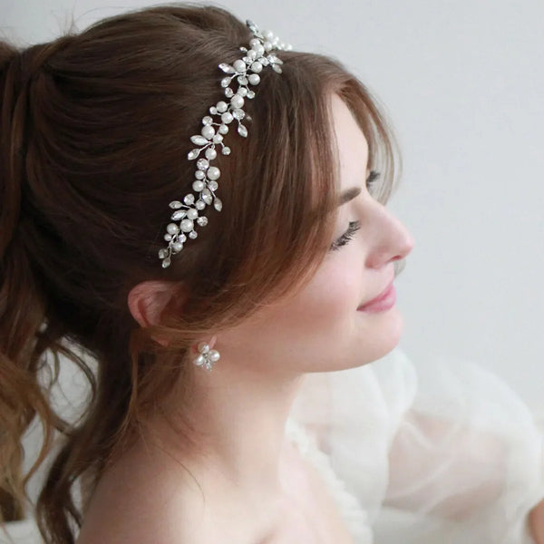A close-up of a woman with brown hair wearing an elegant pearl bridal headband.