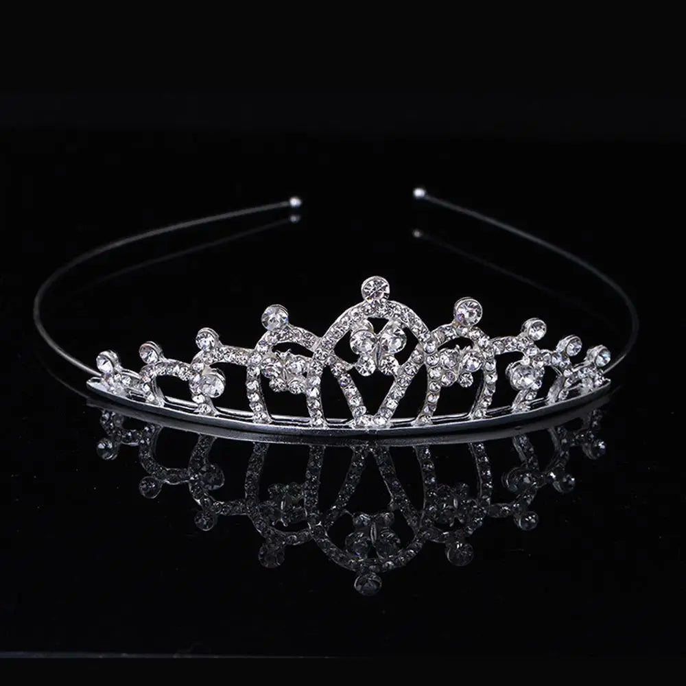 A sparkling crystal hair crown for women, designed in the shape of a royal princess, displayed on a dark reflective surface.