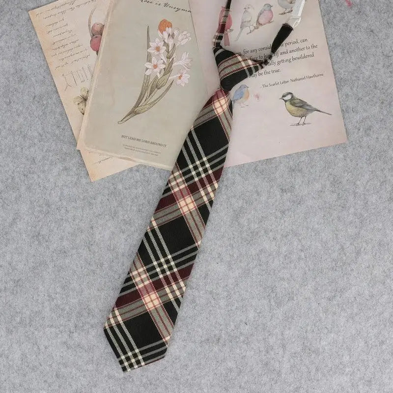 A plaid neck tie featuring black, maroon, and white checks is displayed alongside vintage-style paper and illustrations.