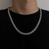 A close-up of a silver stainless steel Cuban link necklace worn around the neck against a black shirt.