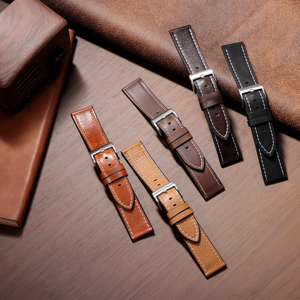 A collection of handmade calfskin leather watch straps in various brown and black shades displayed on a wooden surface.