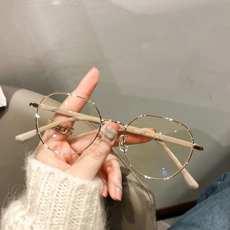 Une main tient une paire de lunettes vintage classiques anti-lumière bleue avec des montures fines en fil de fer sur un fond 