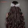 El cabello oscuro de una mujer está adornado con una diadema de novia hecha de borlas de plata y cadenas de aguja.