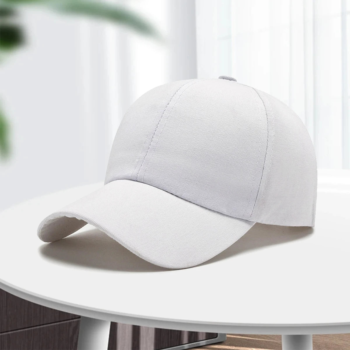 A light gray unisex cotton curved visor hat is displayed on a white table.