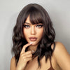 A close-up portrait of a woman modeling a short wavy bob wig with dark hair and dramatic makeup.