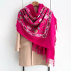 A vibrant magenta floral scarf draped over a beige coat hanger.
