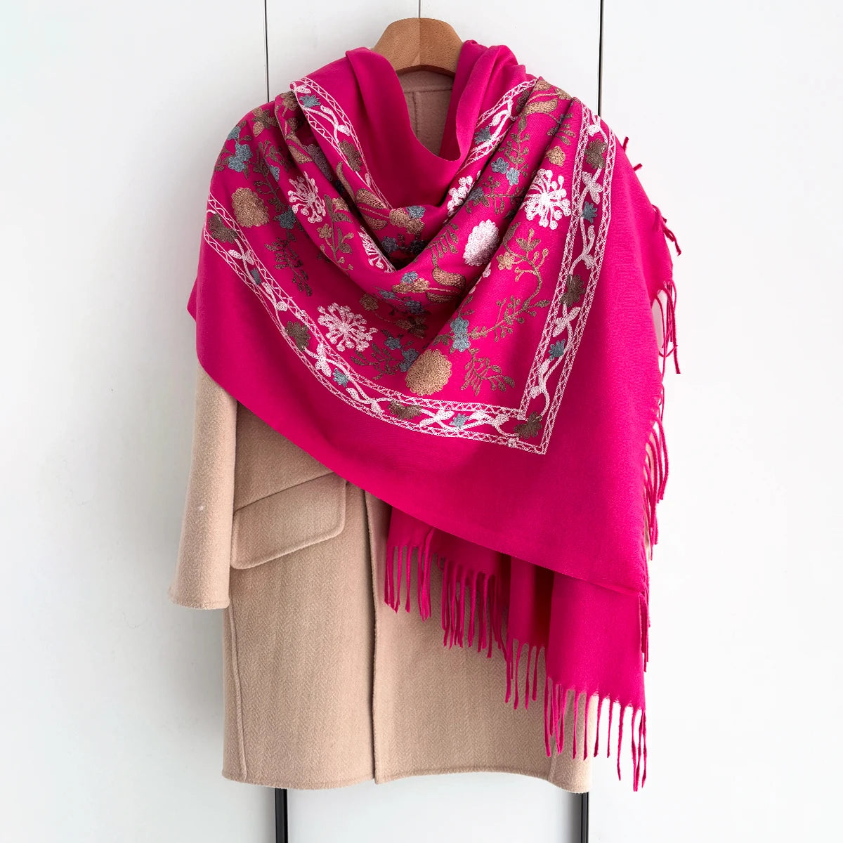 A vibrant magenta floral scarf draped over a beige coat hanger.