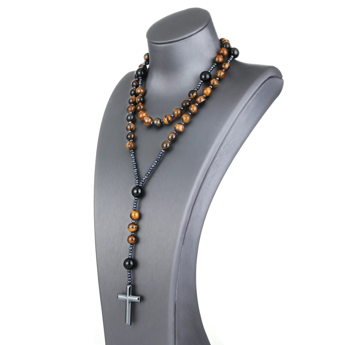 A rosary necklace featuring tiger eye and black agate beads with a hematite cross pendant displayed on a mannequin.
